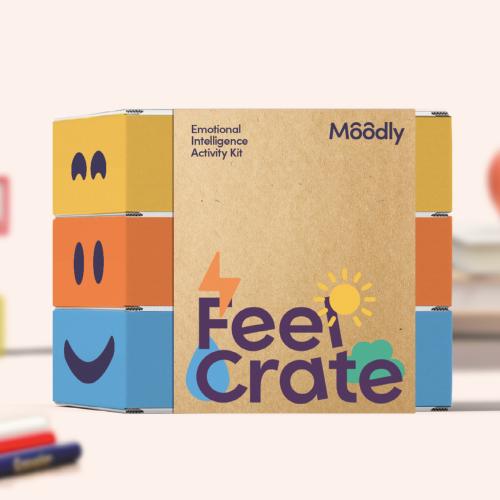 A cardboard package with yellow, orange and blue on the front with a smiling face and the text Feel Crate written on the side.