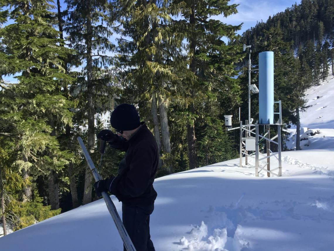 Trevor Dickinson holding a snow tube, used for taking a core snow sample to measure density by weighing the tube