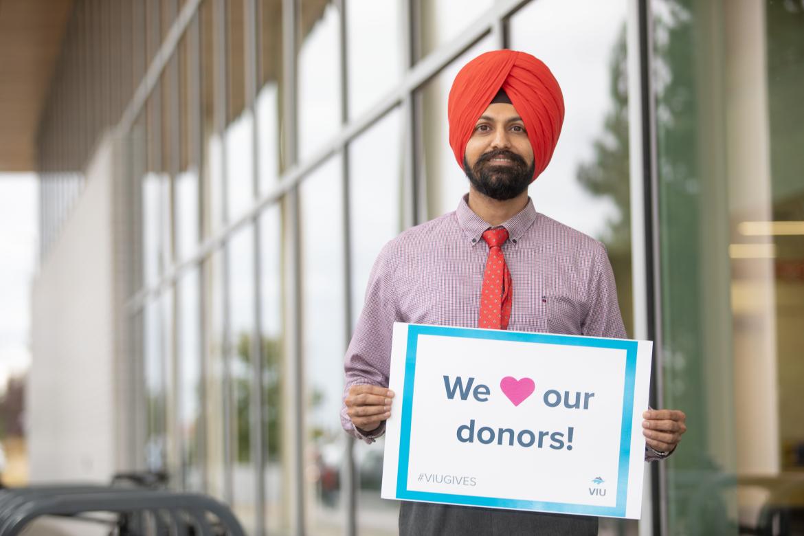 Harpreet outside the Centre for Health and Science holding a sign that reads We love our donors!